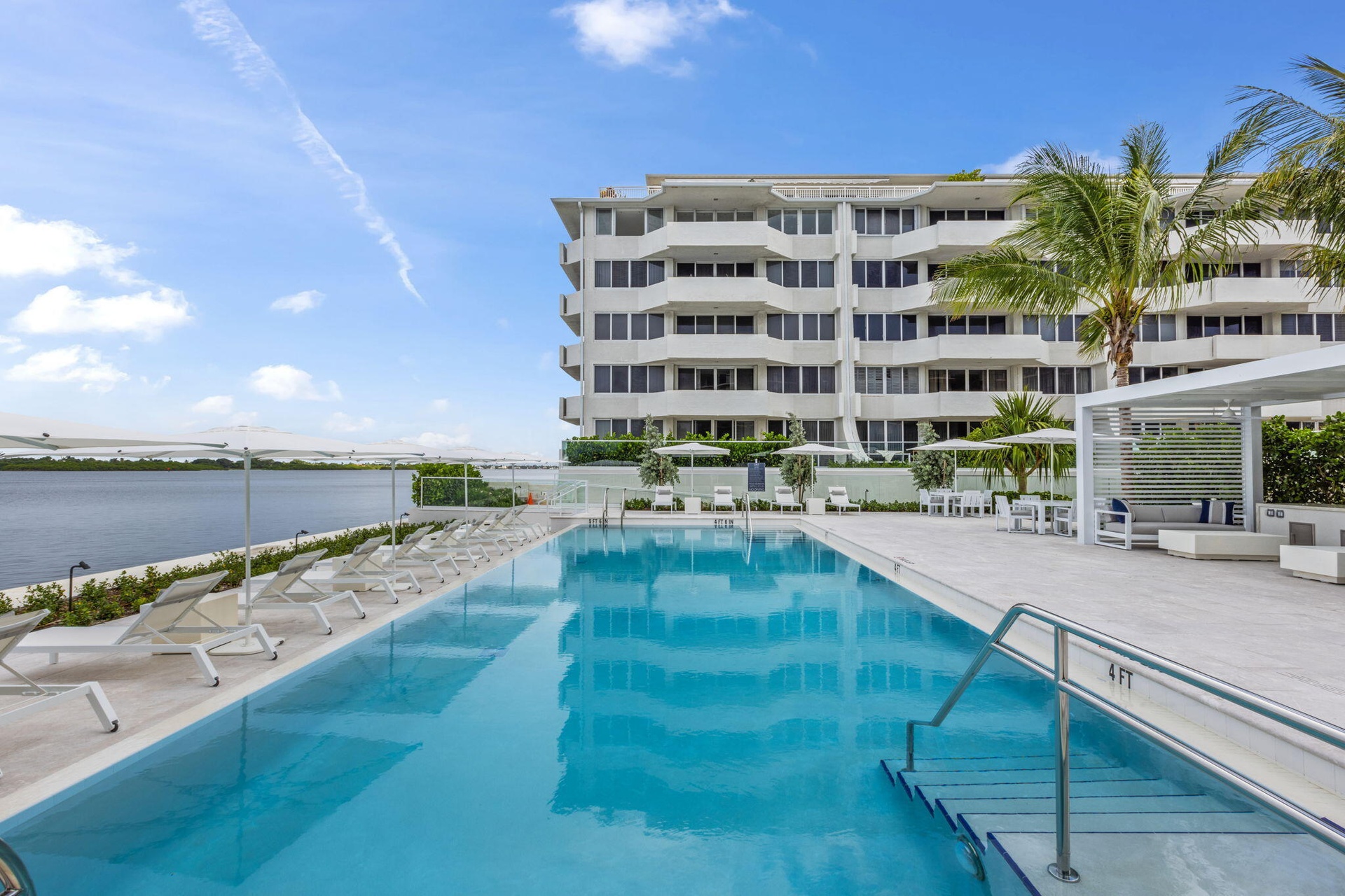 Resort-style pool area featuring a rectangular swimming pool, integrated entry steps, and a surrounding paver deck