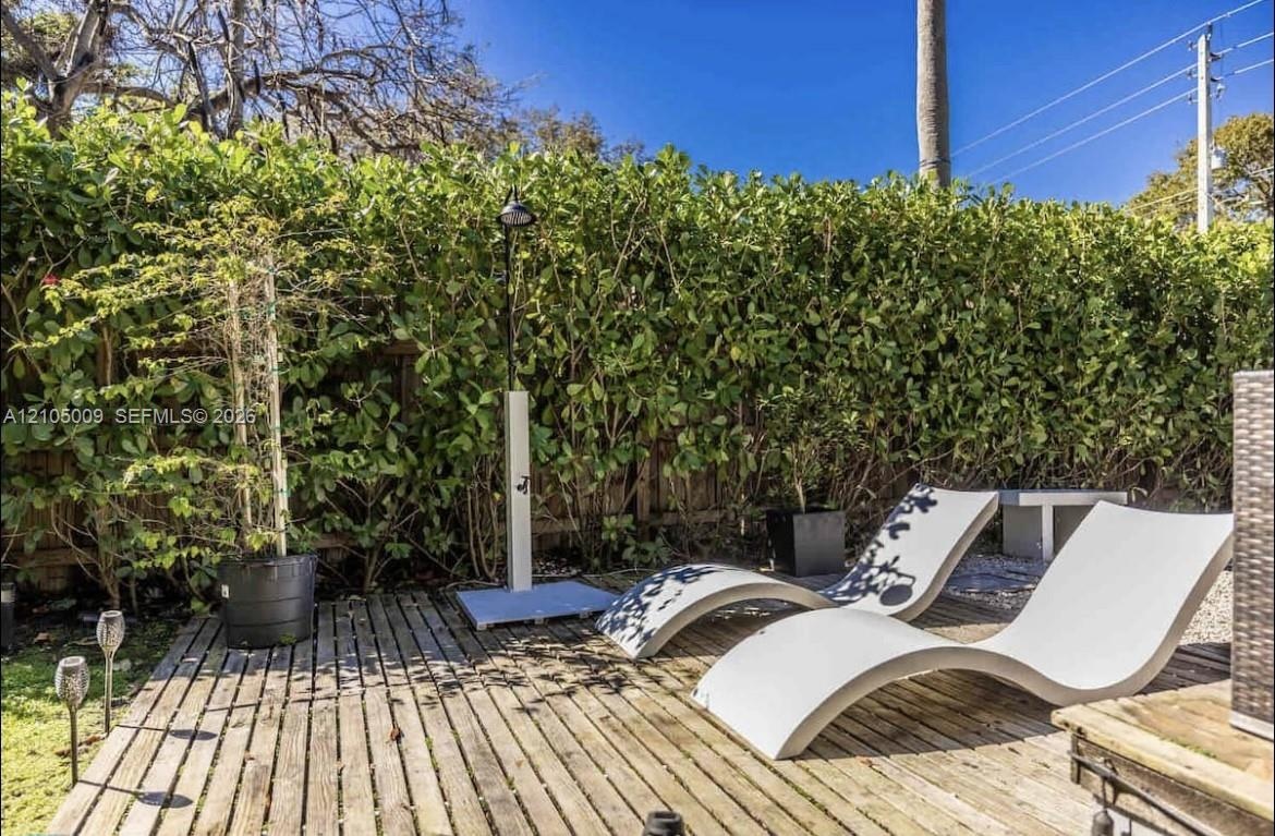 Wood-plank decking with an outdoor shower and lush privacy hedging