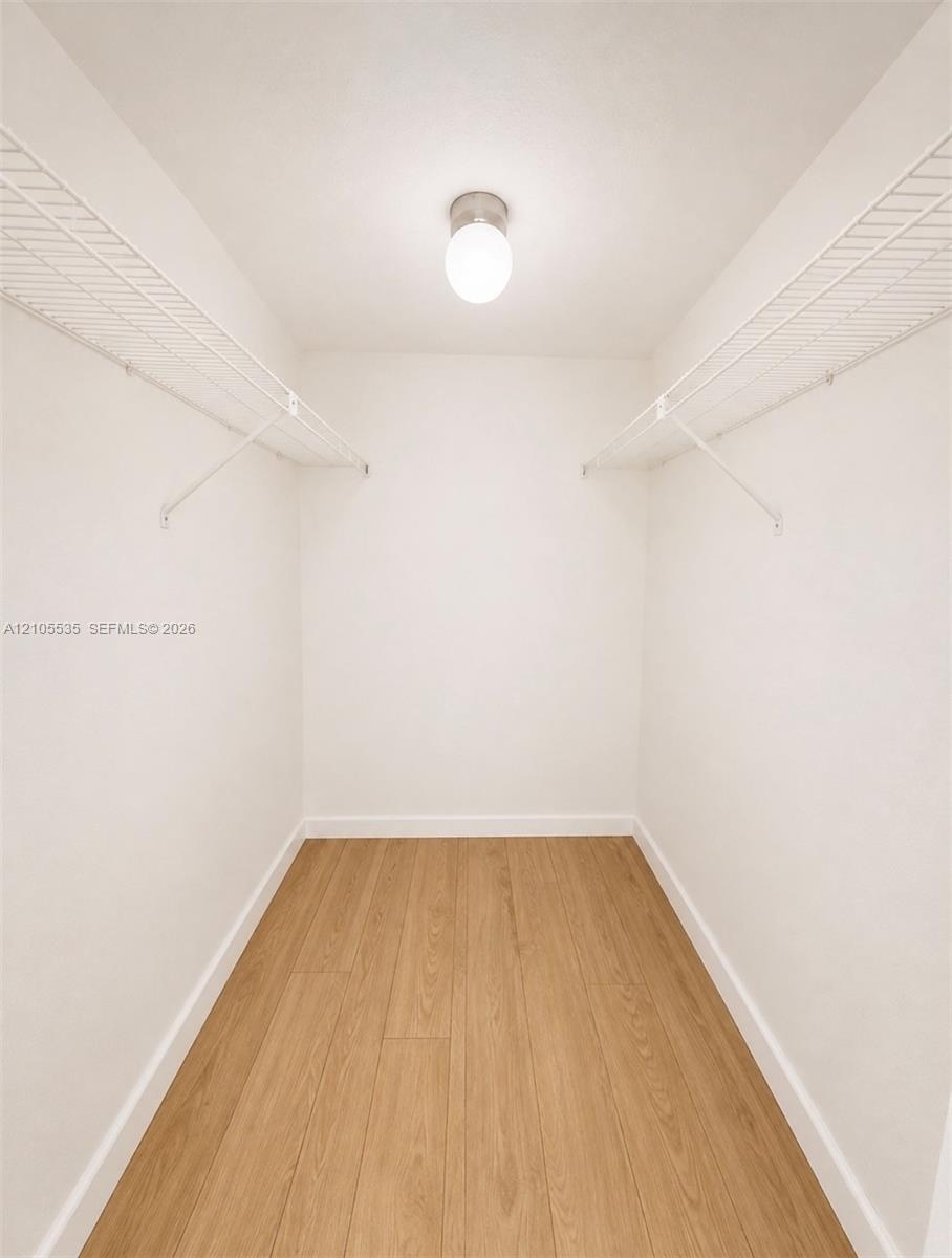 Recessed ceiling light, white walls, wood-finish flooring, and wire shelving