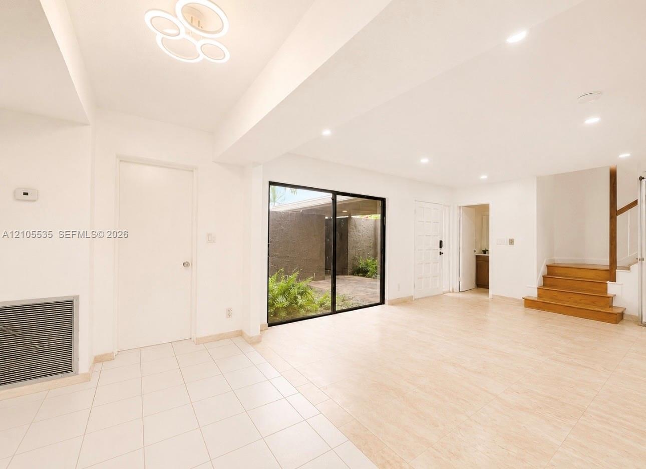 Expansive living space featuring a contemporary ceiling fixture, recessed lighting, and a full-height sliding glass door