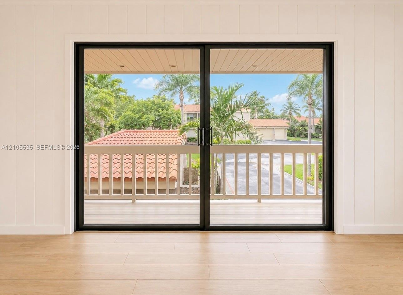 Sliding glass doors with black framing, wood-finish flooring, and white paneled walls