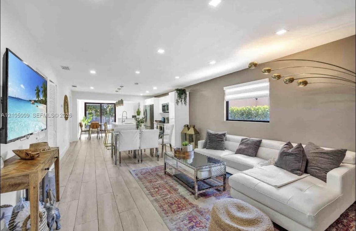 Open-concept living area featuring wood-finish flooring, recessed lighting, and a kitchen with stainless steel appliances