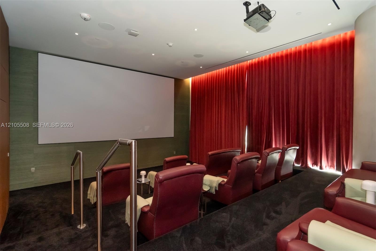 Dedicated theater room featuring a large projection screen and ceiling-mounted projector