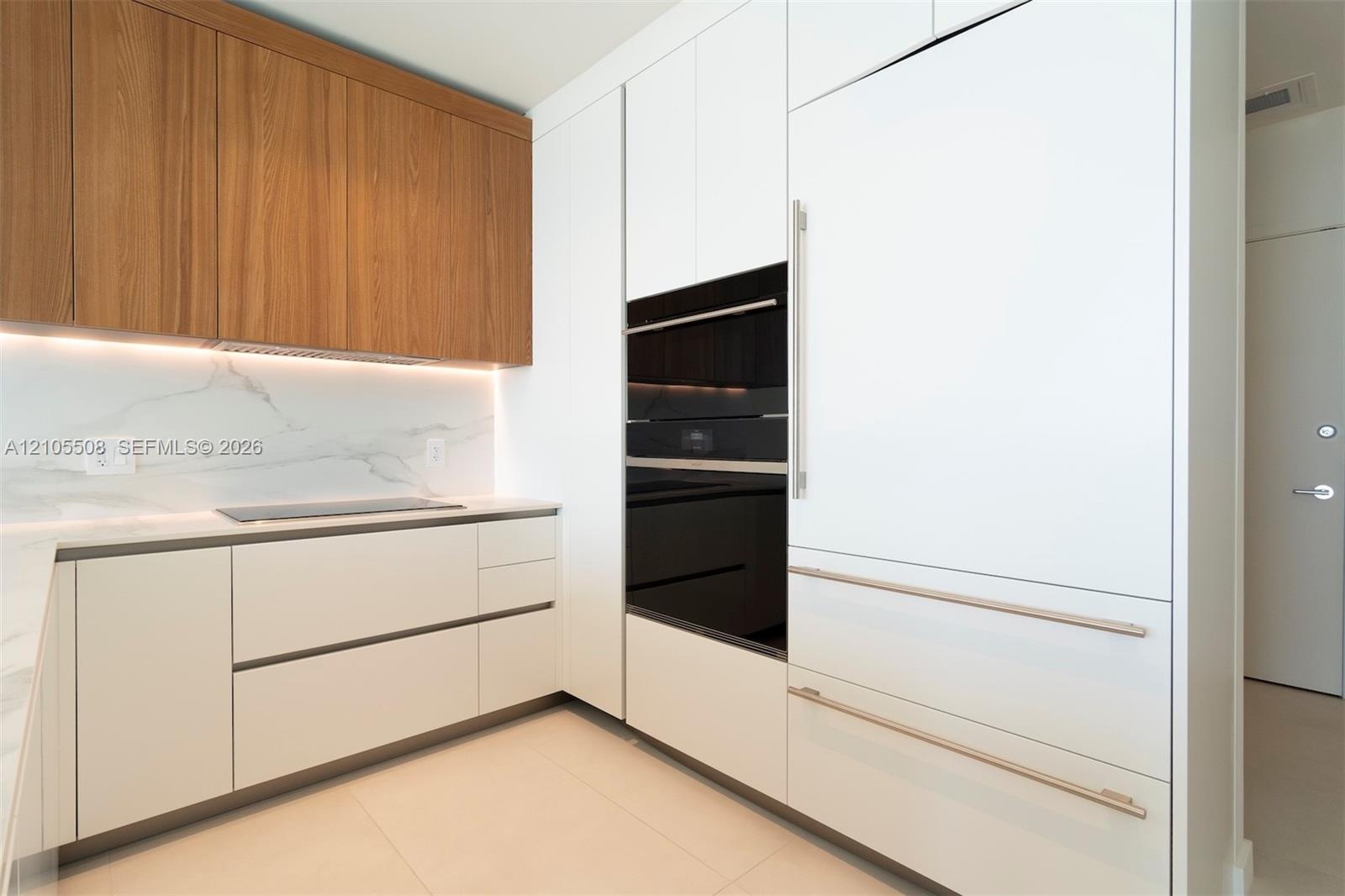 Wood-finish upper cabinetry, integrated appliances, built-in wall oven, induction cooktop, and quartz-finish countertops
