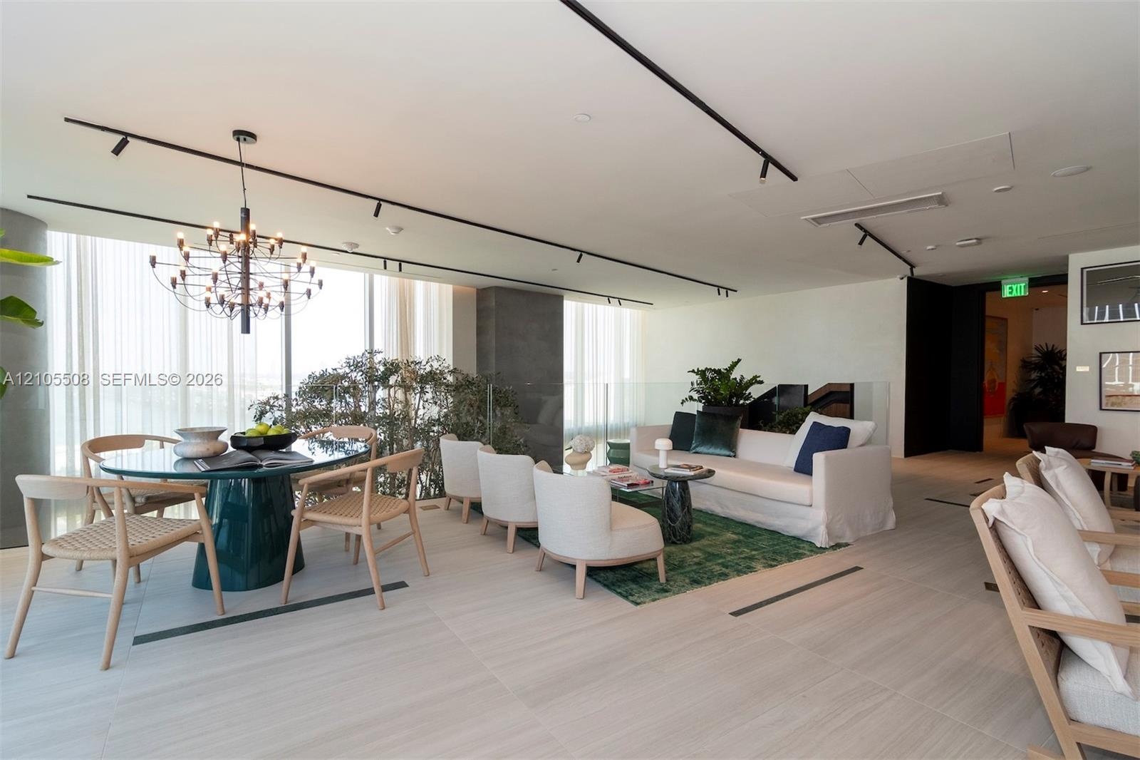 Open-concept living space with expansive windows, a modern chandelier, track lighting, and light-toned tile flooring