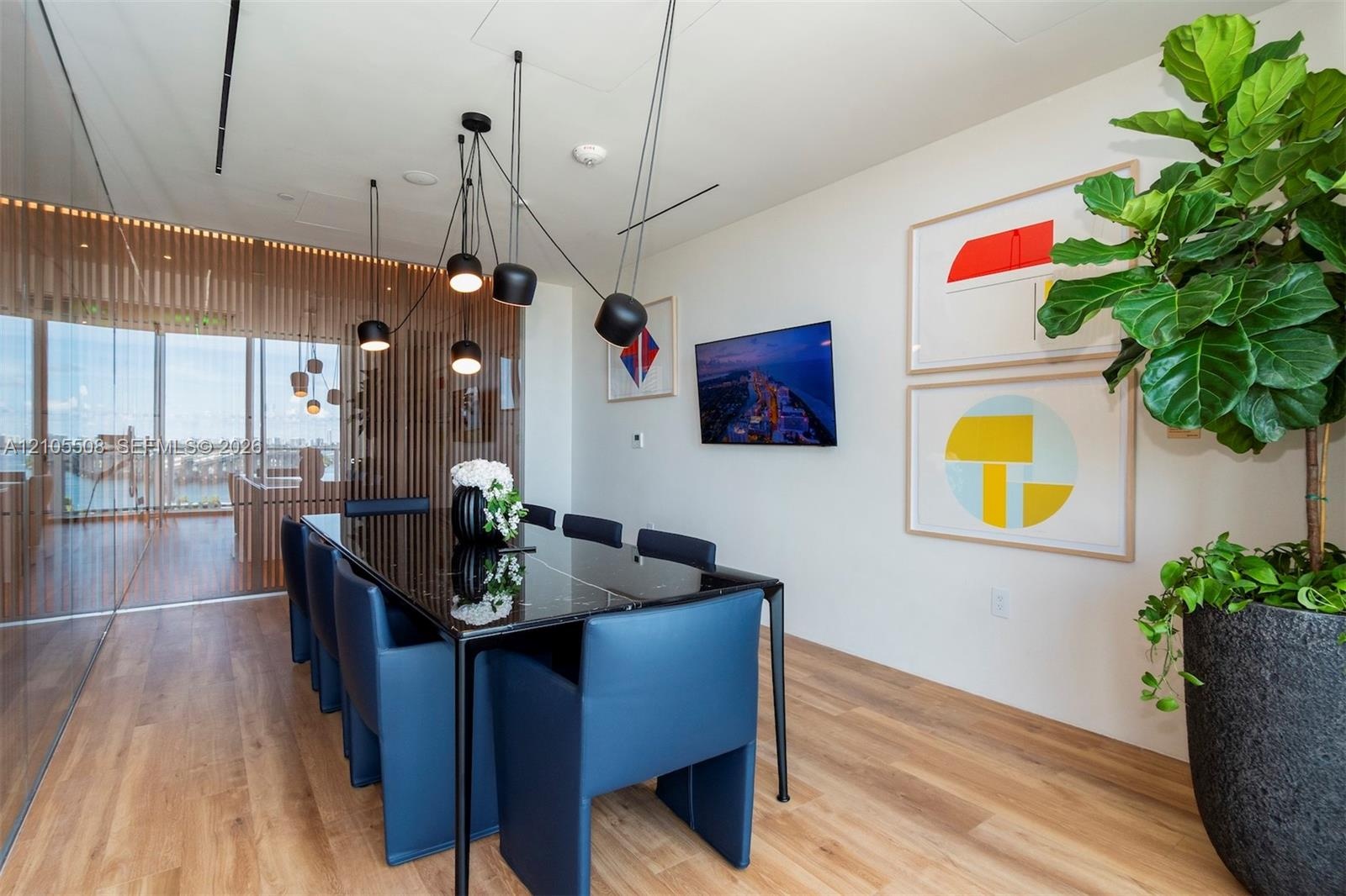 Expansive room featuring wood-finish flooring, a full-height glass wall, and a black slab table