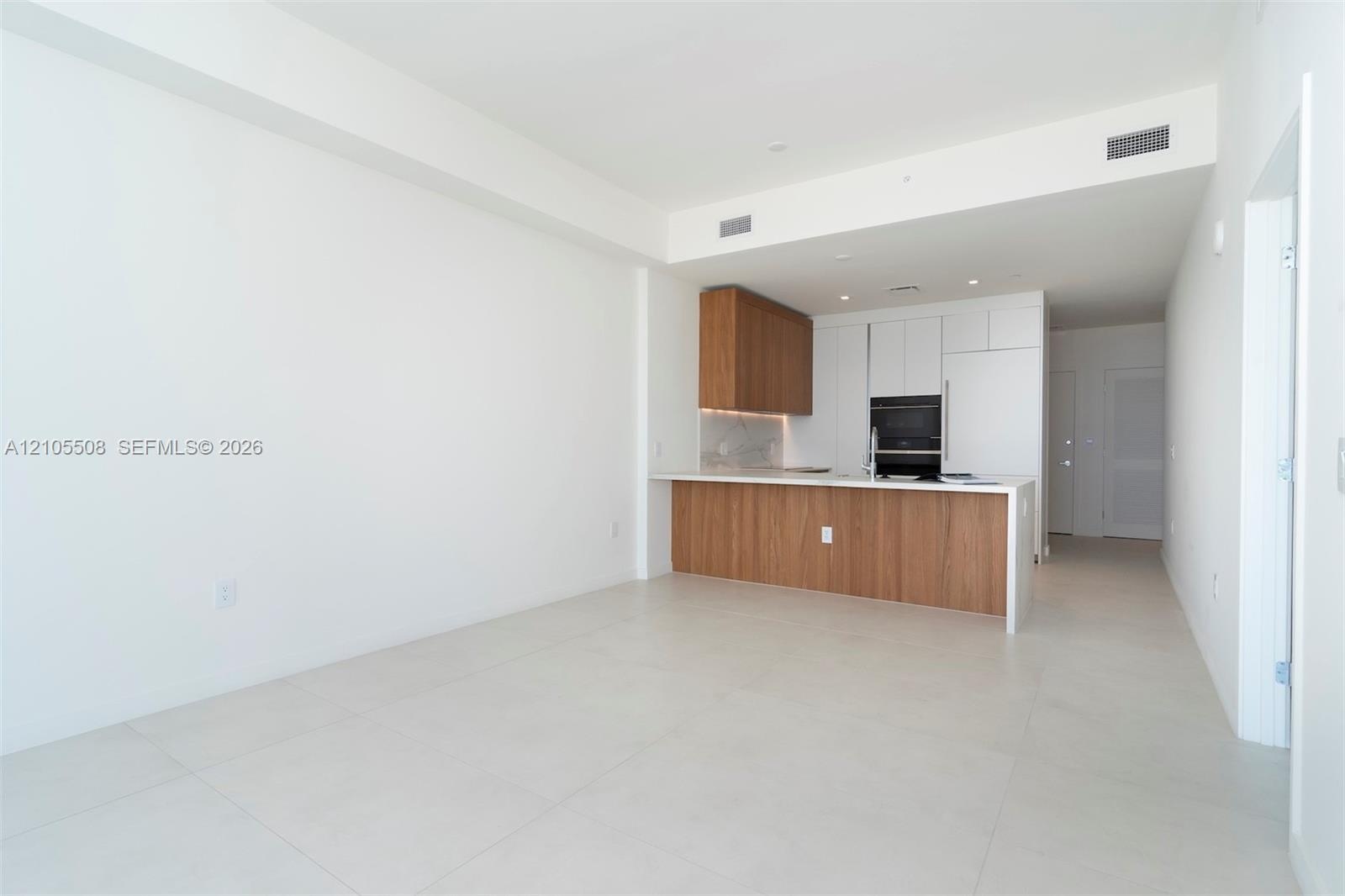 Open-concept kitchen featuring wood-finish cabinetry, integrated oven, and a white countertop with a matching backsplash
