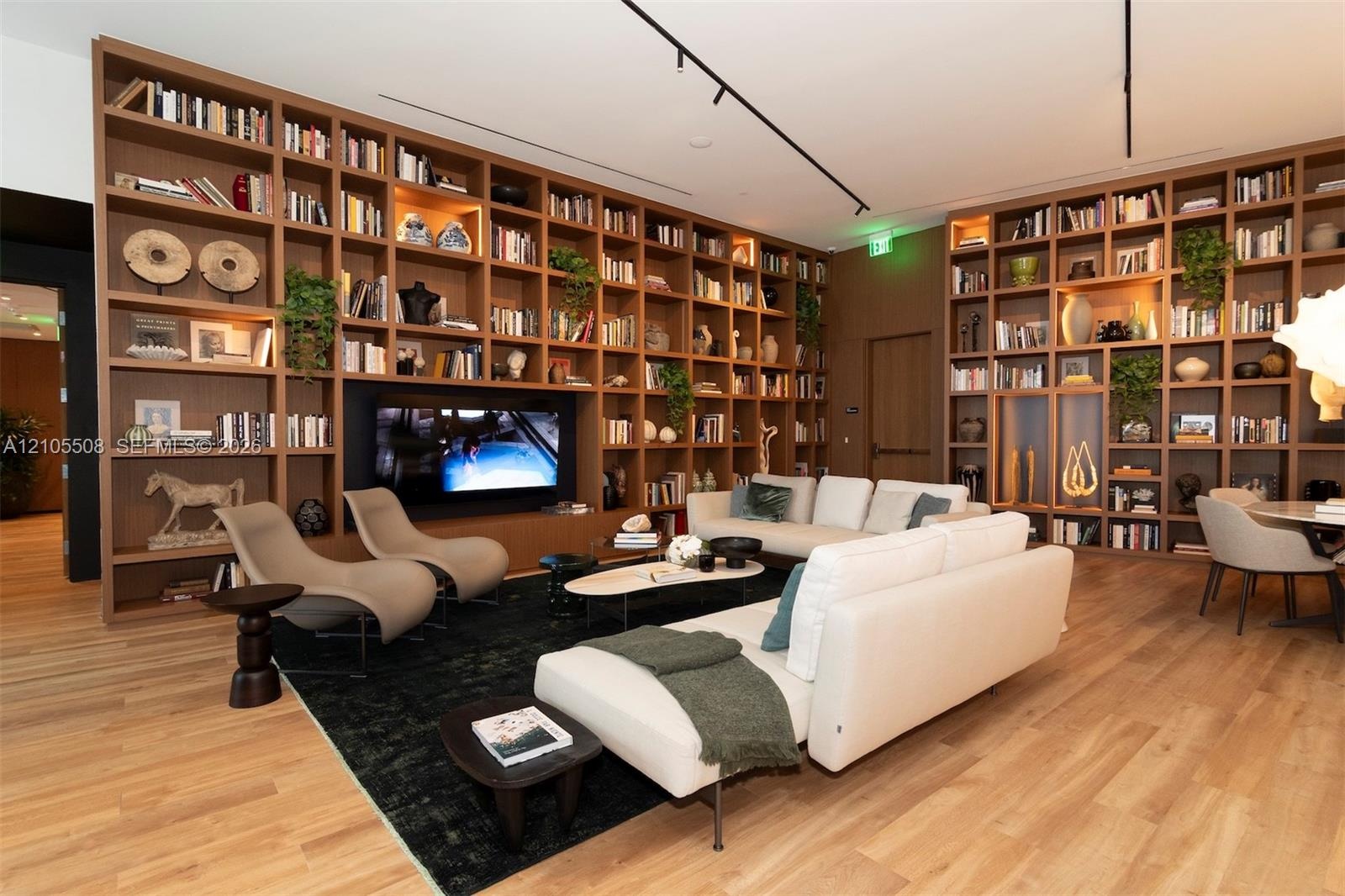 Built-in shelving with integrated lighting, wood-finish flooring, recessed ceiling lights, and track lighting