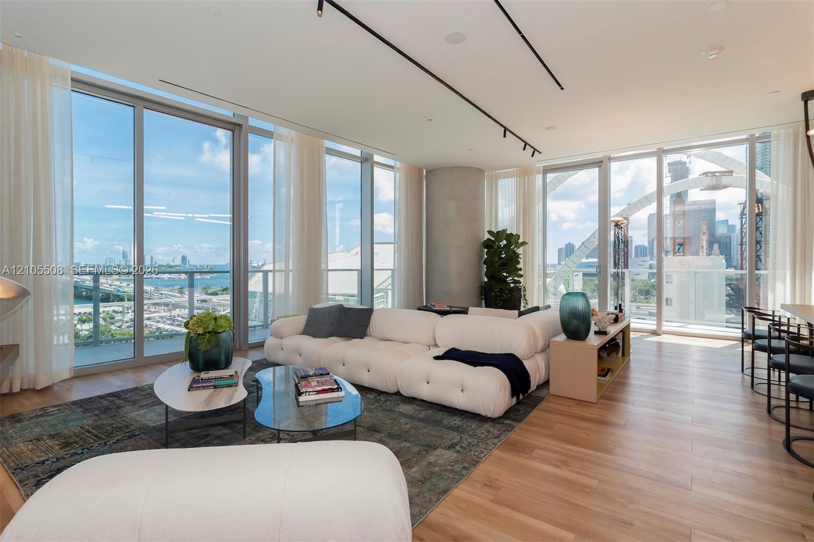 Floor-to-ceiling windows, wood-finish flooring, recessed lighting, and a neutral color palette