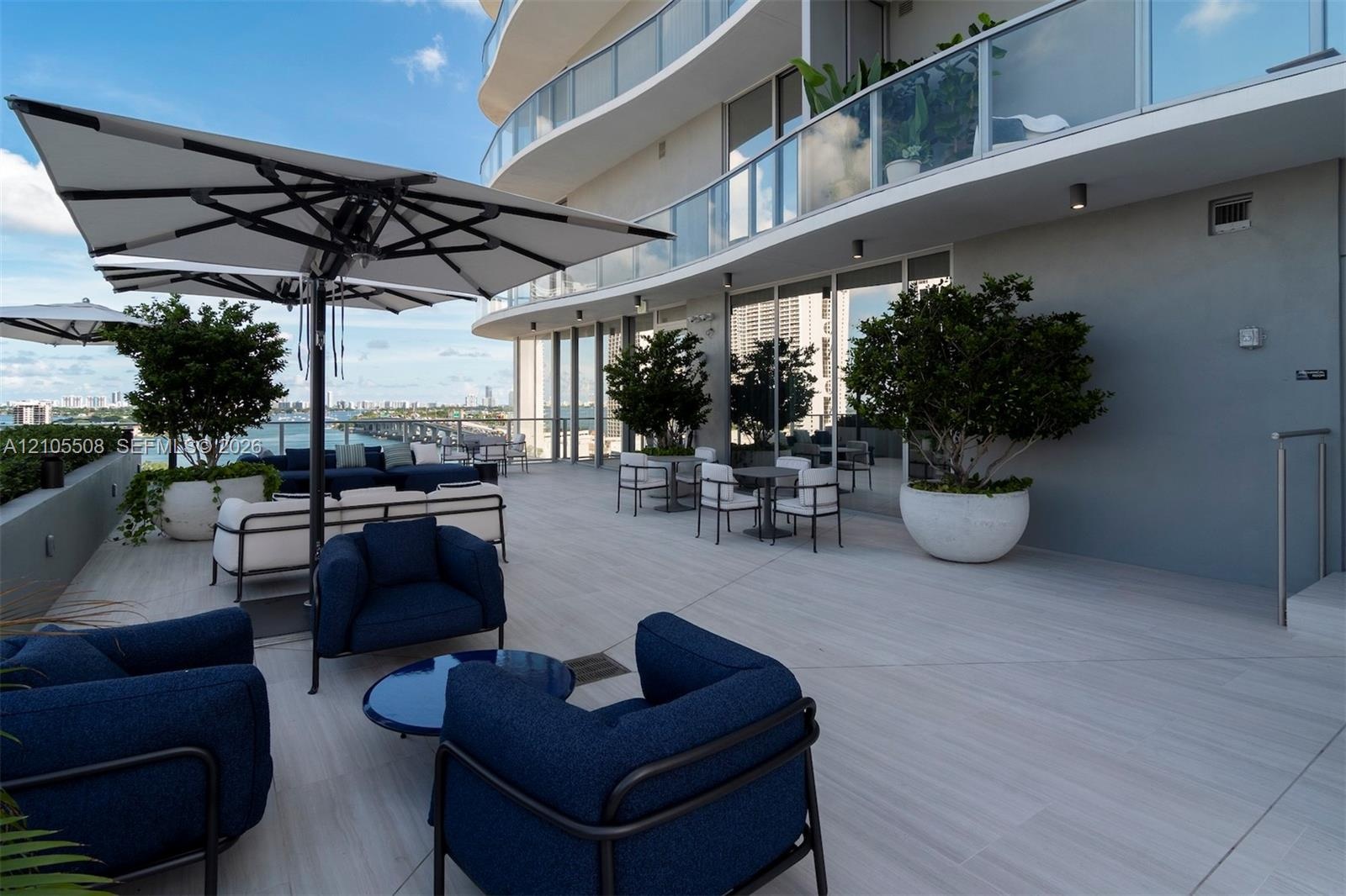 Expansive outdoor terrace featuring light-toned large format tile flooring, modern architectural lighting, and abundant natural light