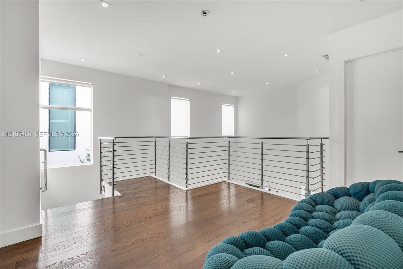 Hardwood flooring, contemporary cable railing, recessed lighting, white walls, and multiple windows
