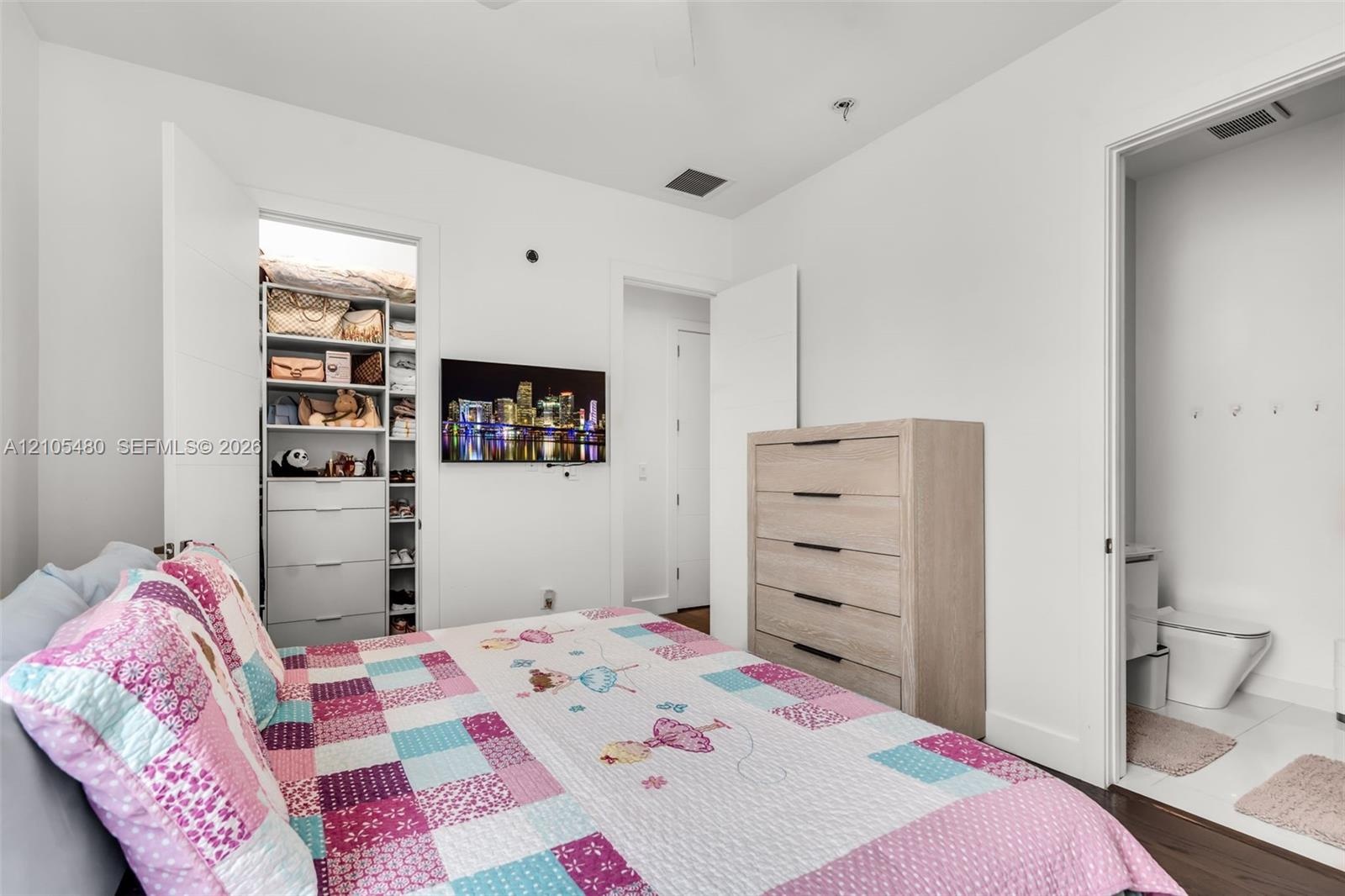 White walls featuring a built-in closet system, dark wood-finish flooring, and a ceiling fan