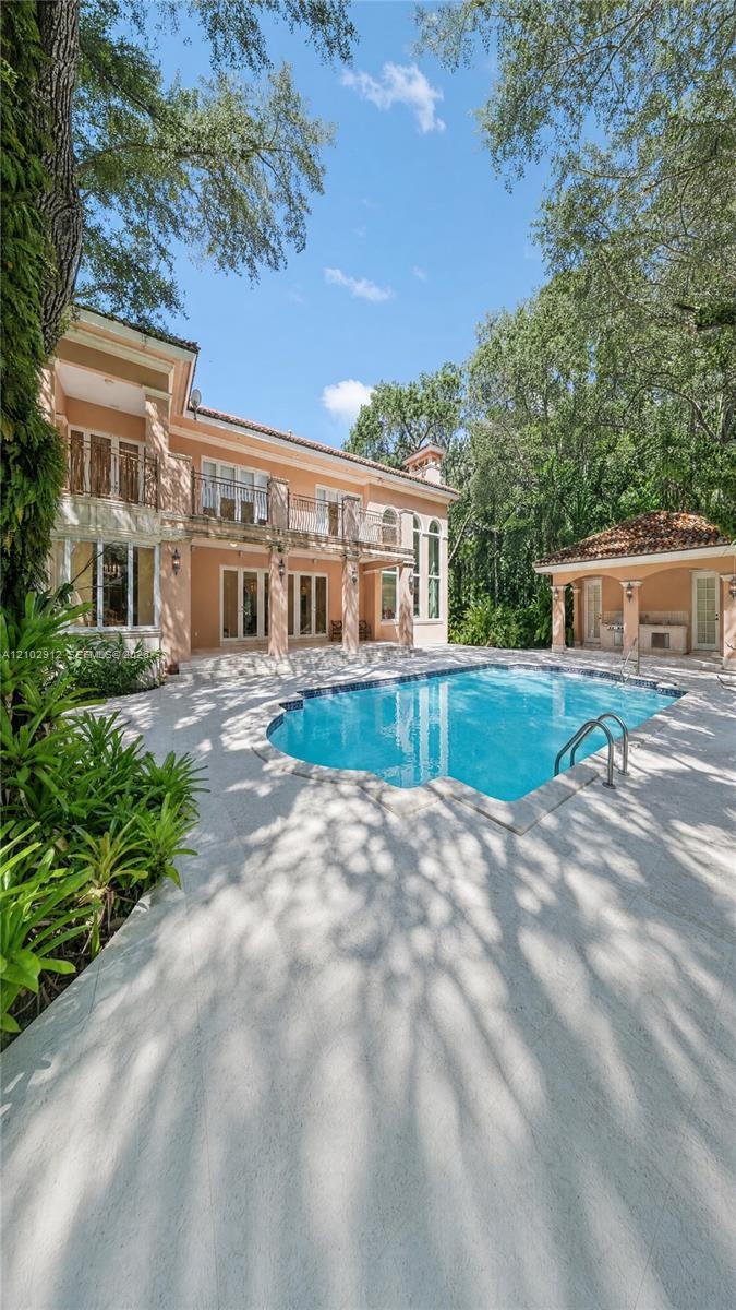 Rectangular swimming pool with integrated stairs, a spacious surrounding deck, and a detached gazebo structure