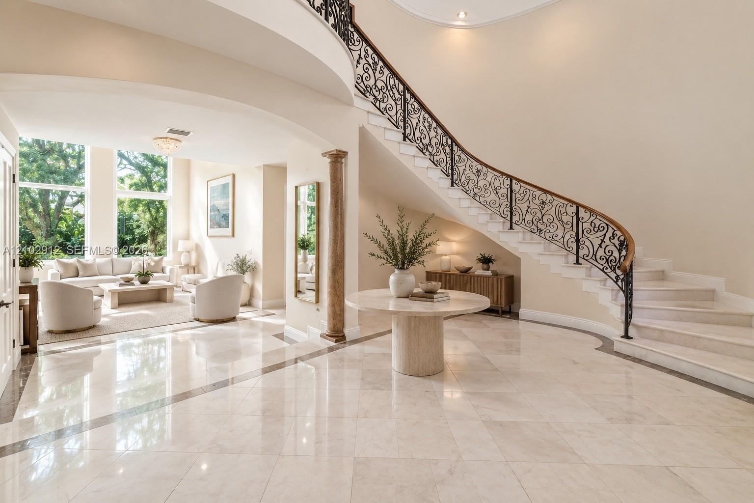 Grand foyer featuring a curved staircase with ornate wrought iron railing and wood handrail