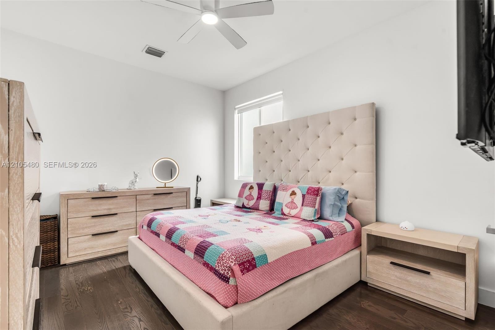 Dark wood-finish flooring, white walls, recessed window, and ceiling fan with integrated lighting