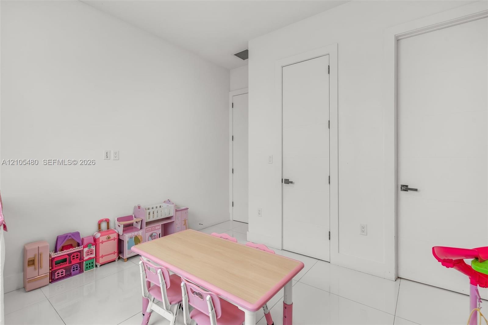 White walls with multiple doors, white tile flooring, and flush-mounted ceiling lighting
