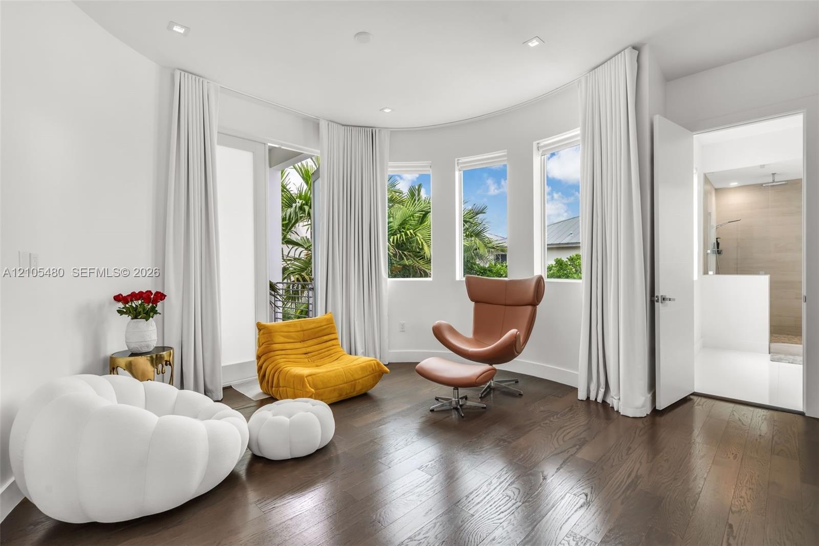 Curved wall with multiple windows, dark wood-finish flooring, recessed lighting, and a white interior door