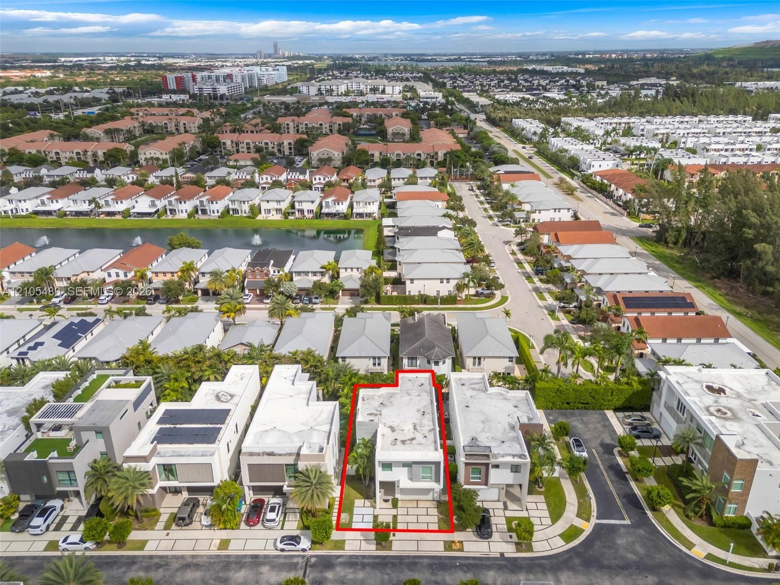 Aerial perspective of a multi-story residential property with a flat roof, situated in a community featuring varied architectural styles and establish