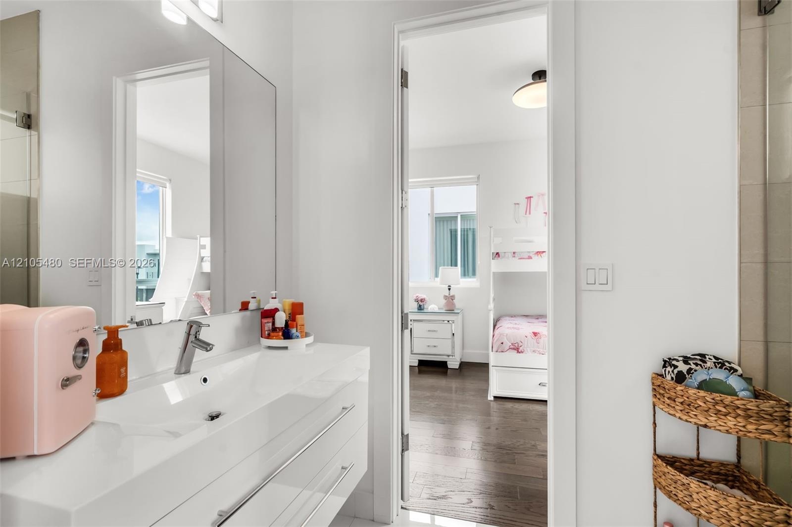 Bathroom featuring a single vanity with an integrated sink, polished chrome faucet, and expansive mirror
