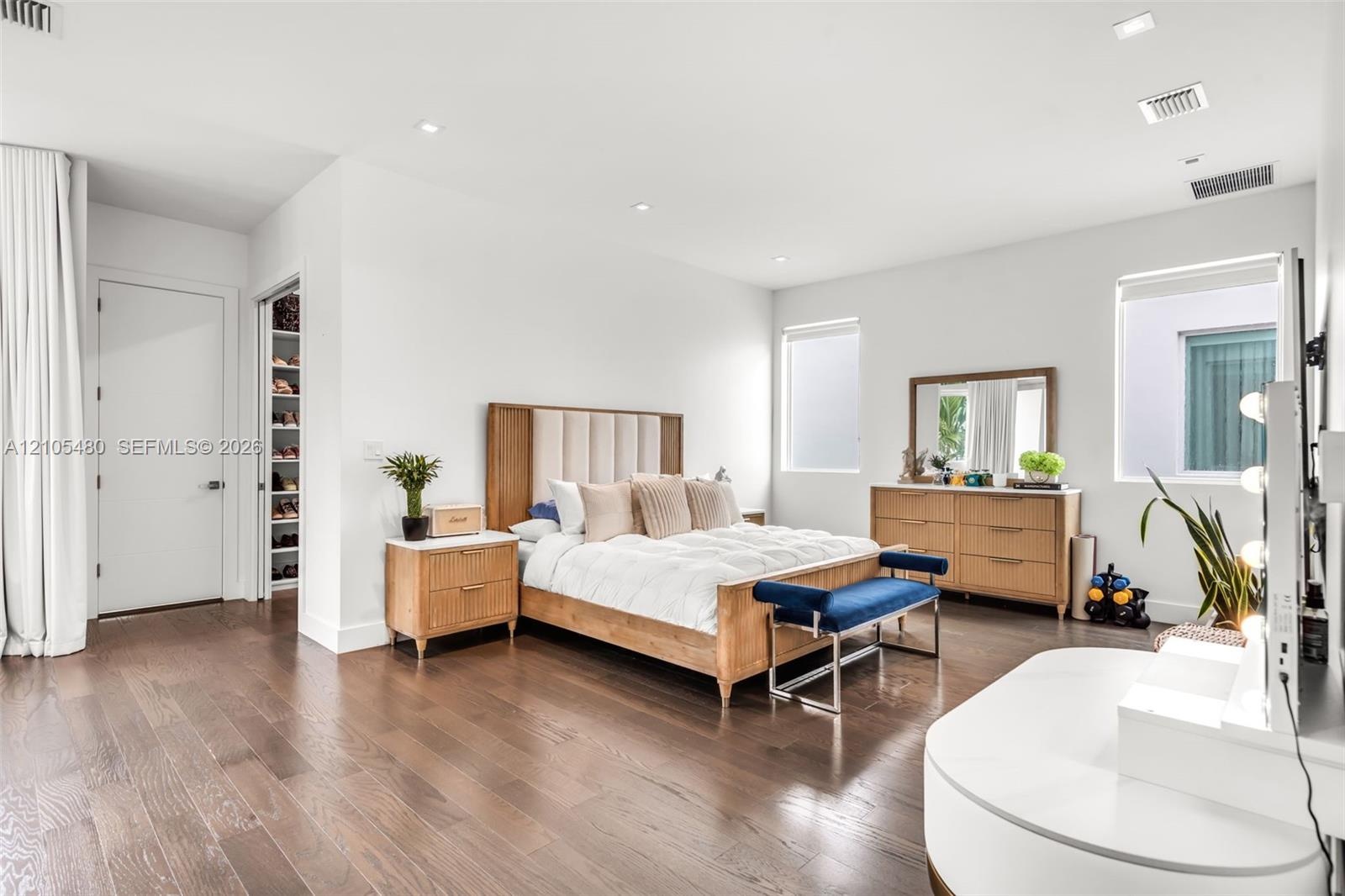 Dark wood-finish flooring, recessed lighting, white walls, multiple windows, and a built-in closet with shelving