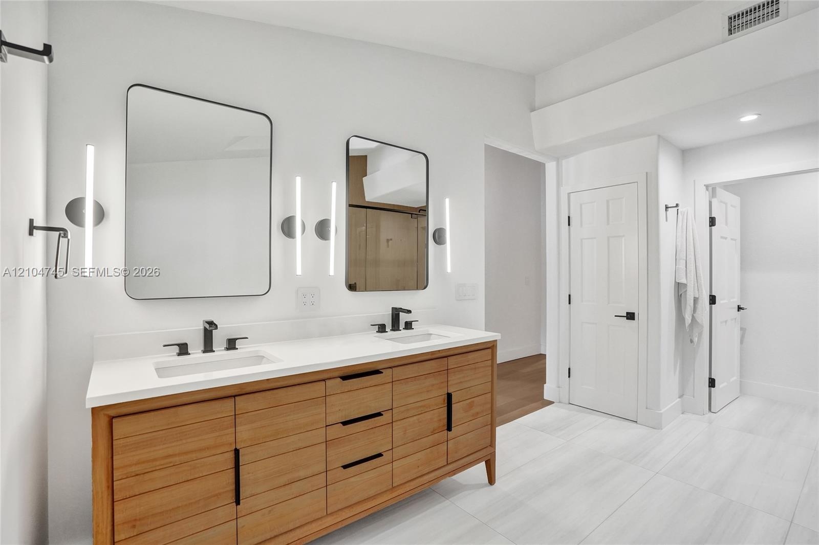 Double vanity with a light wood-finish cabinet, white countertop, and rectangular undermount sinks