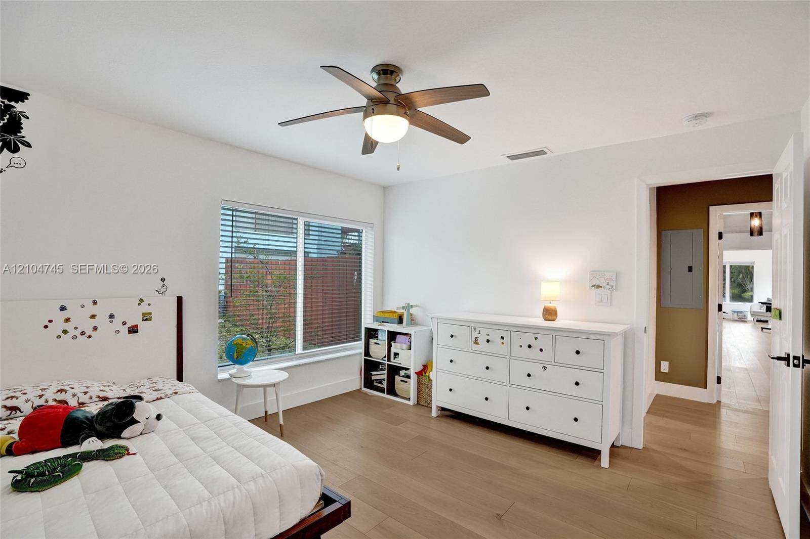 Wood-finish flooring throughout, white walls, and a recessed window with blinds