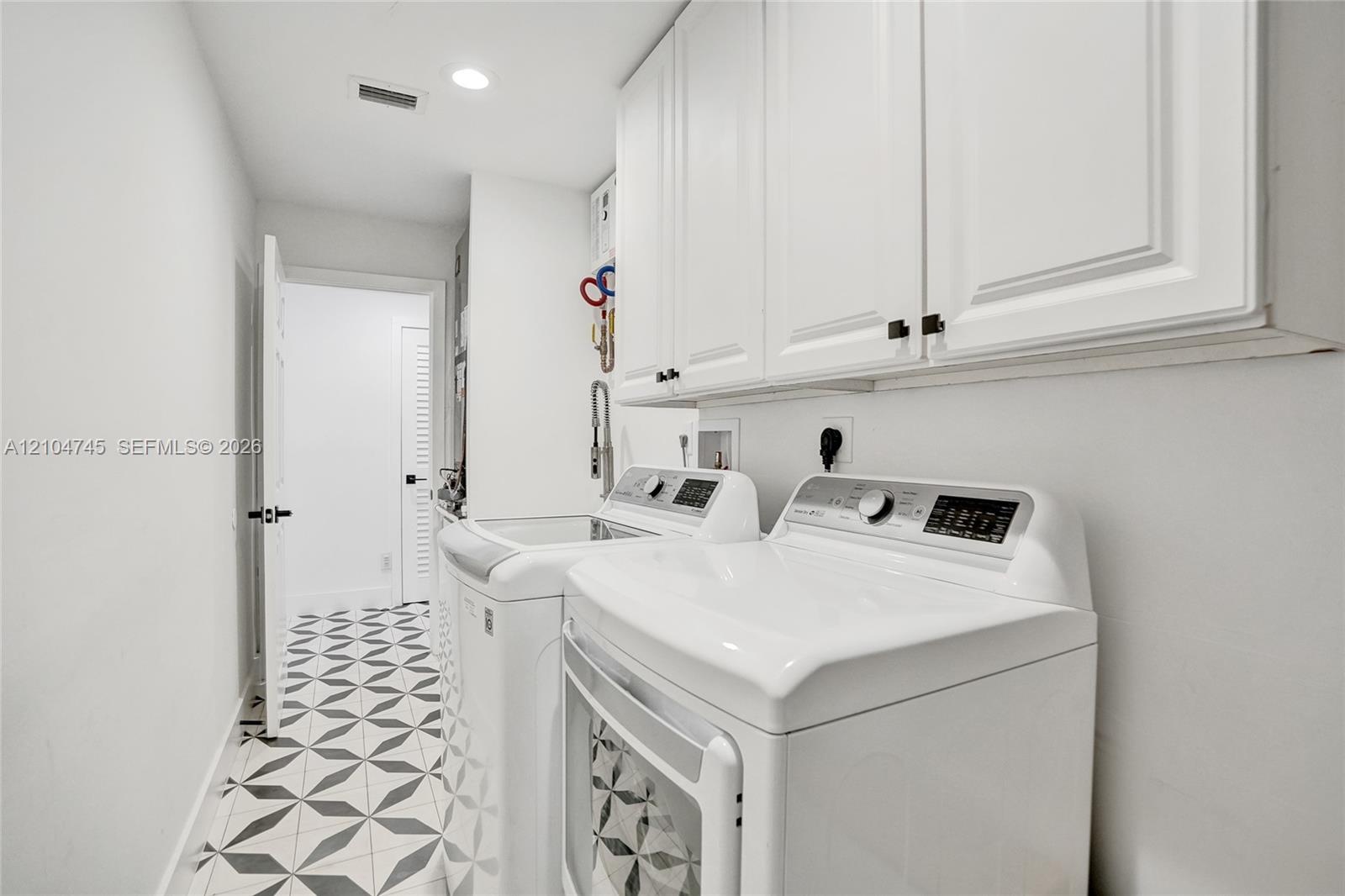White shaker cabinetry, recessed lighting, and patterned floor tiling