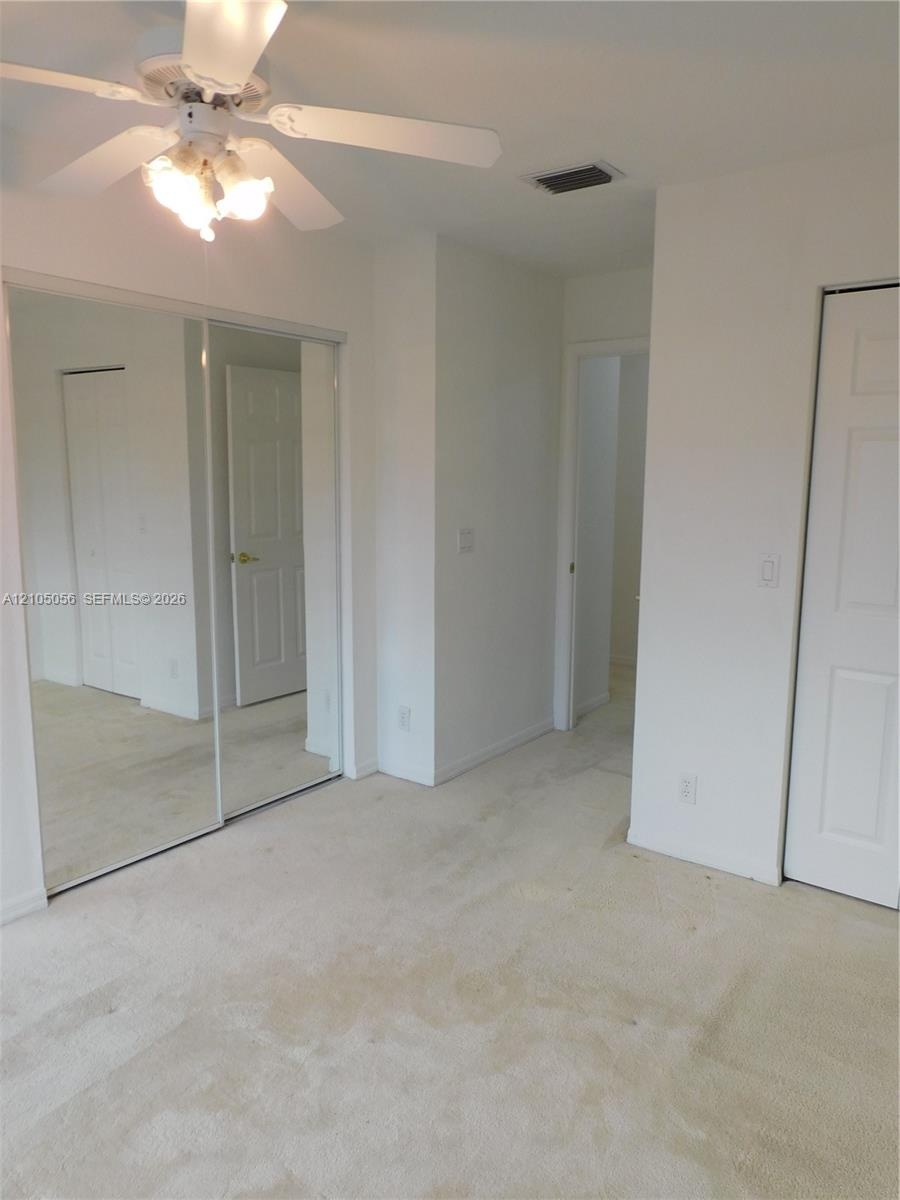 Enclosed patio with full-height windows, neutral tile flooring, and a water backdrop
