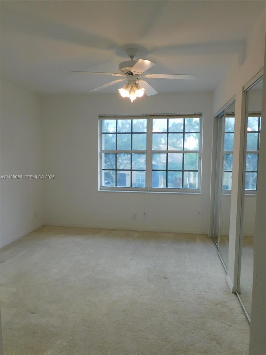 Screened sunroom with expansive waterfront vistas, featuring floor-to-ceiling windows, tile flooring, and mature landscaping with native trees framing