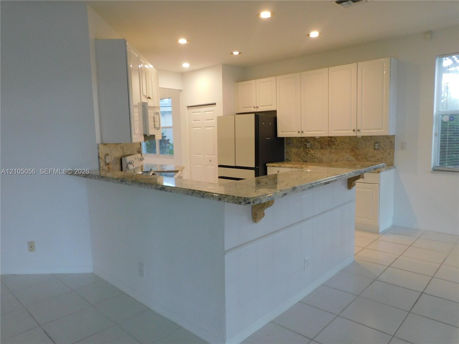 Kitchen featuring white cabinetry, granite countertops, and recessed lighting