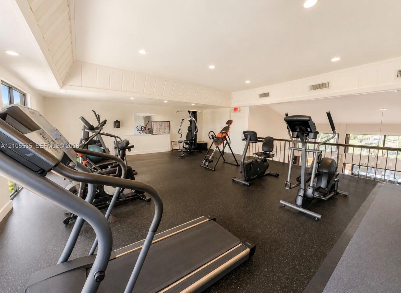 Spacious fitness area featuring rubber flooring, recessed lighting, and various exercise equipment