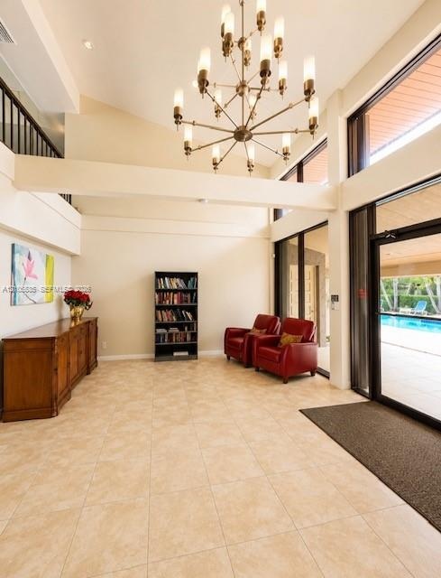 Vaulted ceilings with exposed beams, large format tile flooring, a multi-tier chandelier, and expansive windows