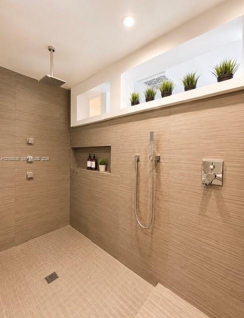 Walk-in shower with a rain showerhead, handheld shower fixture, and a built-in niche