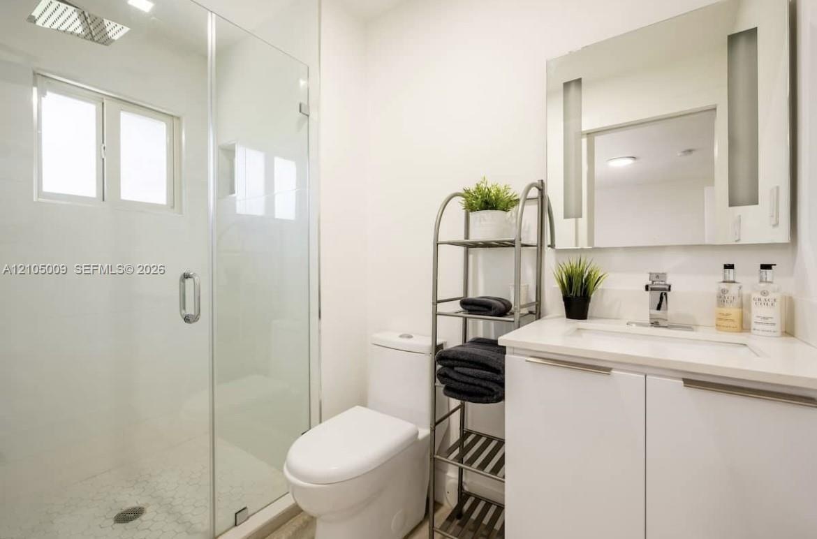 Glass-enclosed shower with white tiled walls and a hex-tile floor