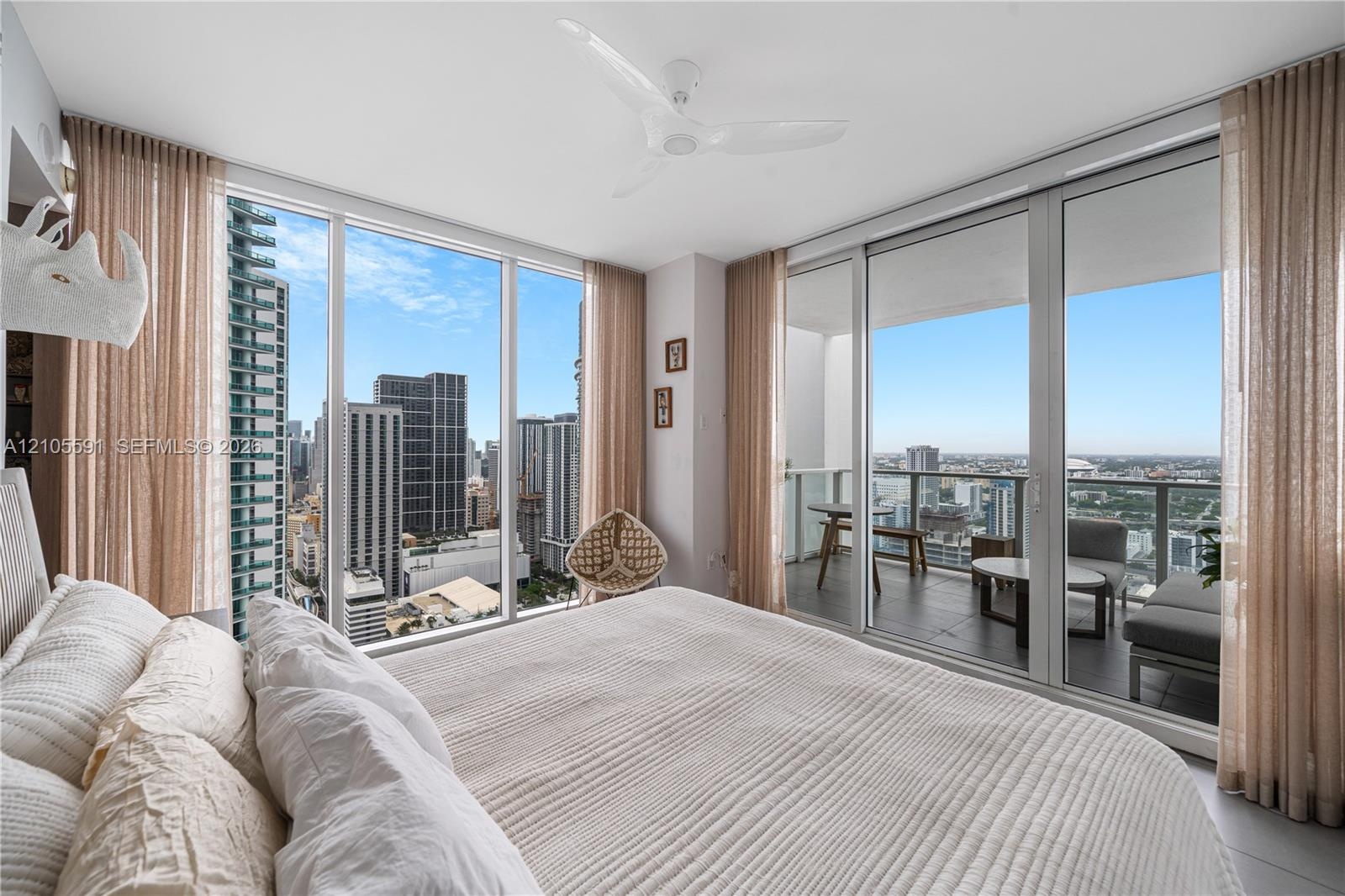 Floor-to-ceiling windows, sliding glass door to a private balcony, ceiling fan, and recessed lighting