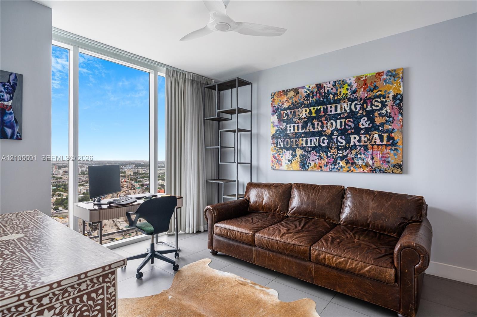 Expansive floor-to-ceiling windows, gray tone walls, a ceiling fan, and gray tile flooring