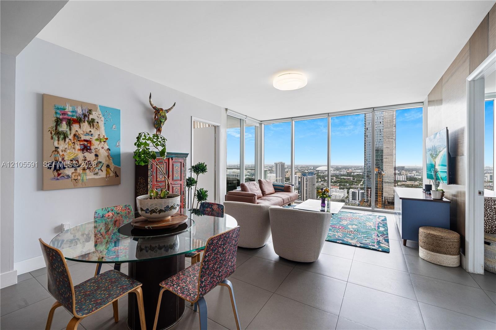 Floor-to-ceiling windows, light gray tile flooring, open-concept living space, built-in ceiling light fixture, and city skyline