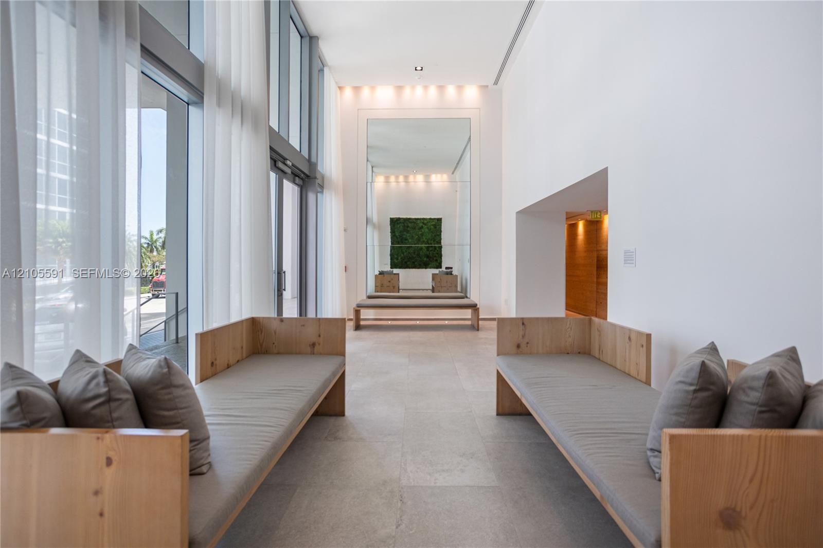 Expansive lobby featuring full-height windows with sheer drapery, recessed lighting, and tile flooring