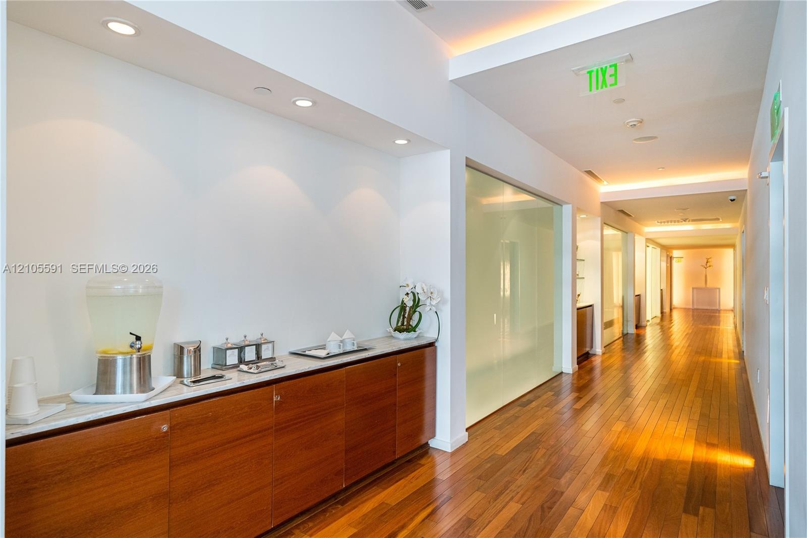 Wood-finish flooring throughout, recessed lighting, built-in wooden cabinetry with a light-colored countertop, and frosted glass panels