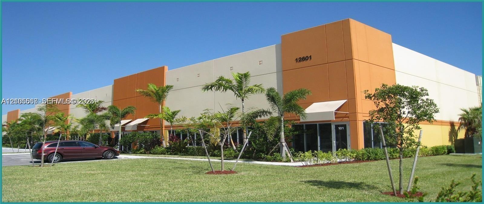 Commercial building with a tan and orange exterior, multiple entryways, and mature landscaping