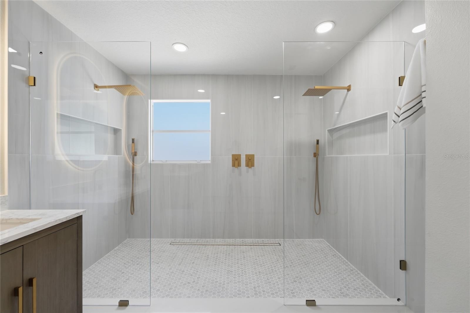 Oversized walk-in shower with largeporcelain tile and dual rainfall heads