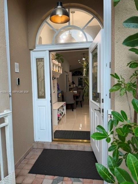 Entryway featuring an arched transom window, a white paneled door with decorative glass inserts, and a bronze-finish pendant light fixture