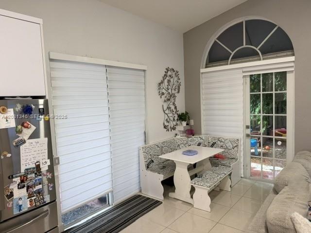 Arched transom window, sliding glass patio door, tiled flooring, white cabinetry, and recessed lighting