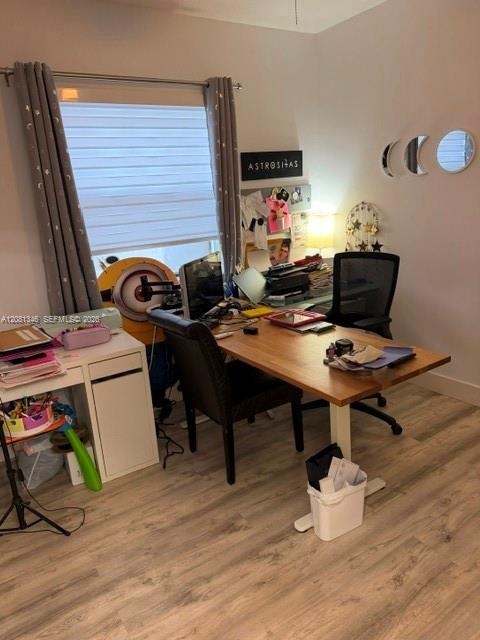 Wood-finish flooring with neutral wall paint and a single window with horizontal blinds
