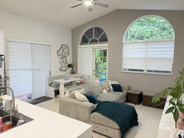 Vaulted ceiling with a ceiling fan, white tile flooring, and arched transom windows