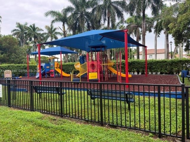Playground featuring multiple slides, shade canopies, and a protective fence