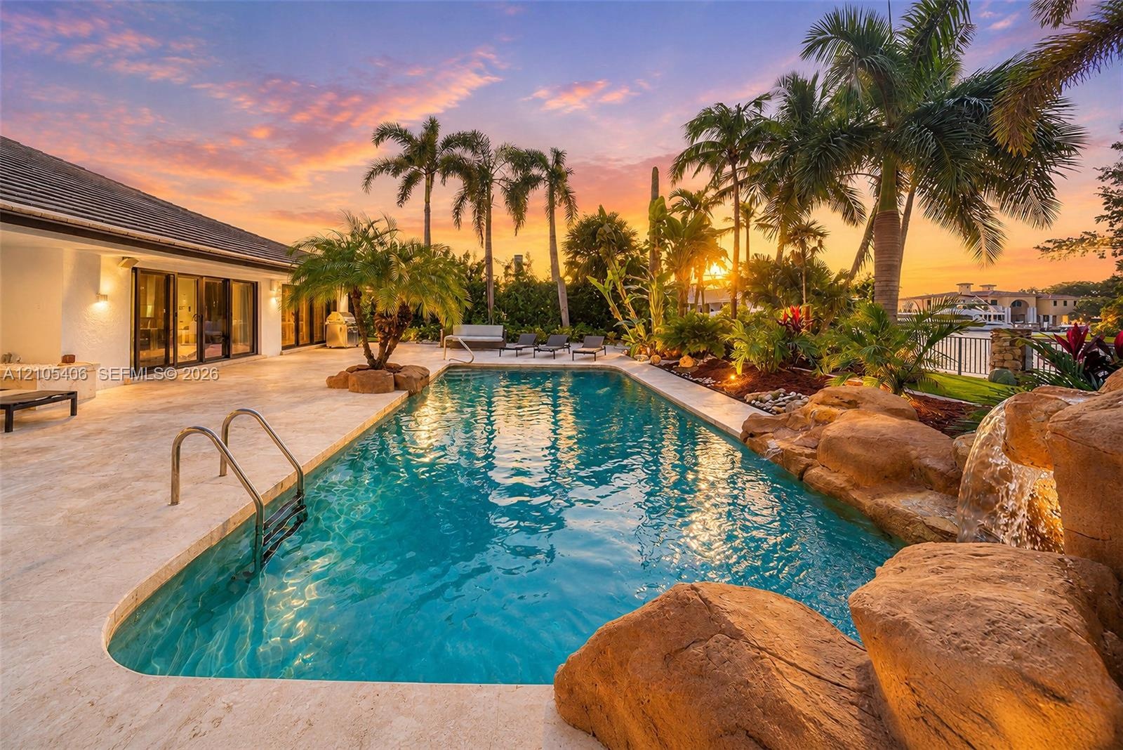 Expansive outdoor area featuring a swimming pool, rock waterfall, and integrated lighting