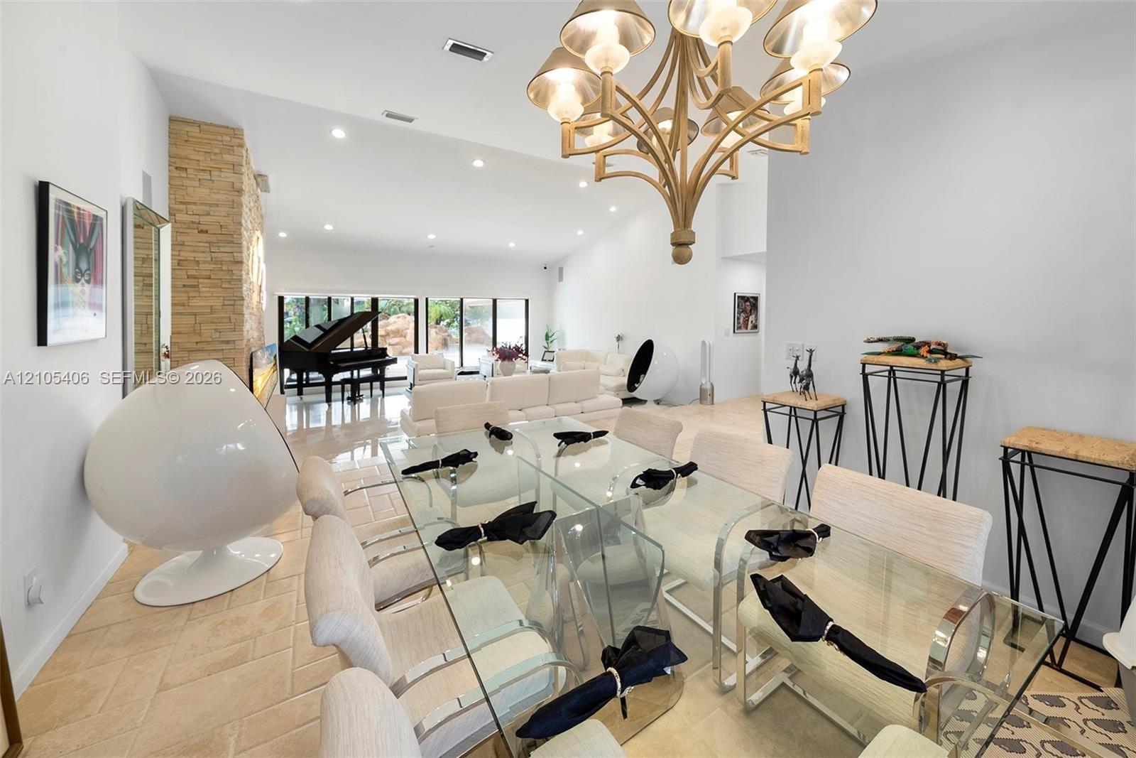 Open-concept living space with tiled flooring, a stone accent wall, and recessed lighting