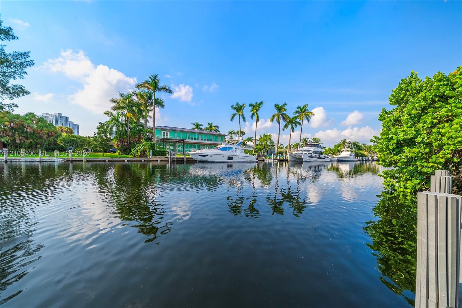 Waterfront property featuring a private dock, mature palm trees, lush landscaping, and direct canal access