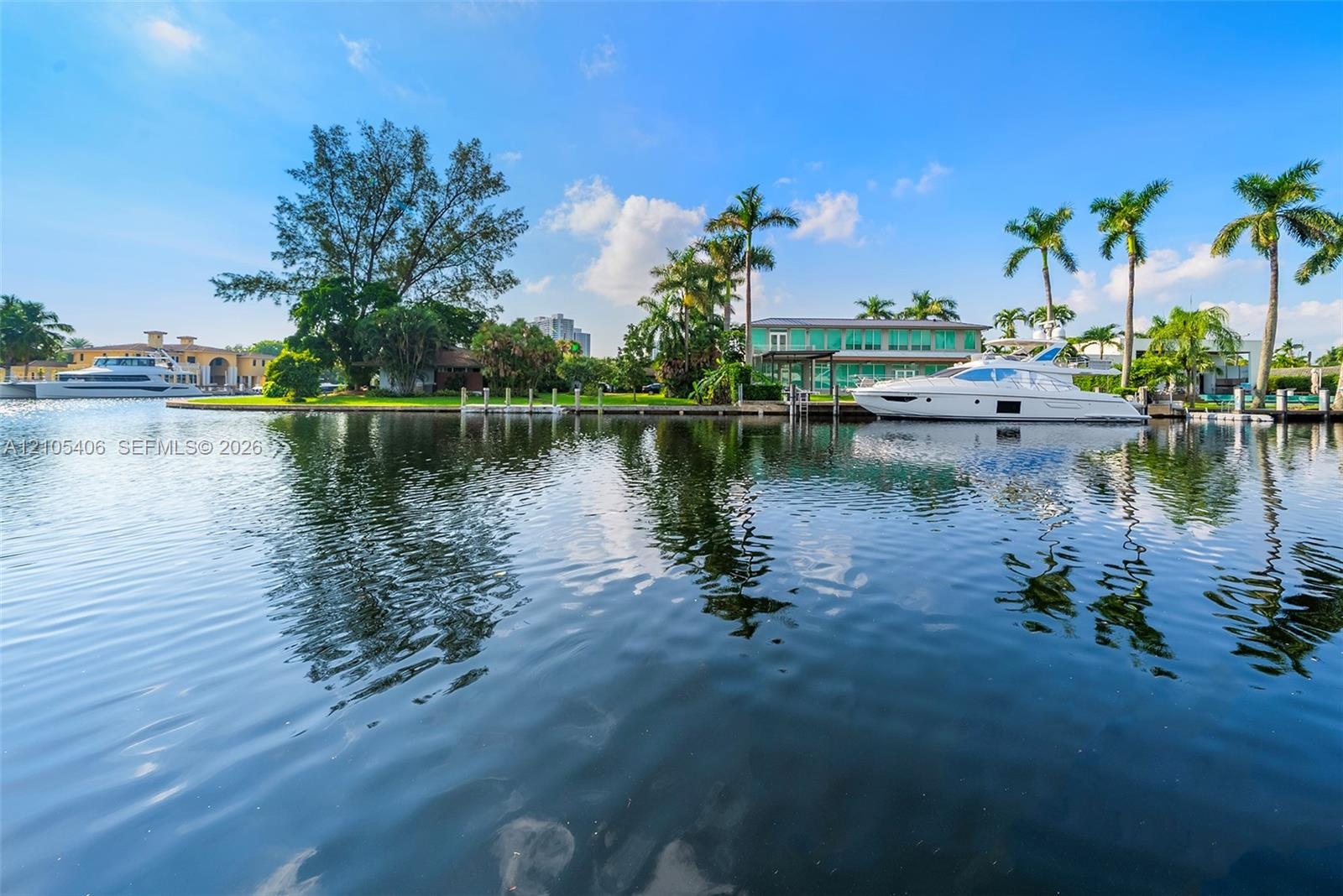 Waterfront property with private boat dockage, mature palm trees, and manicured lawn